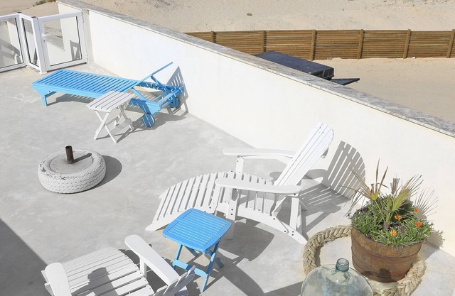 House situated by the sea, on a long white sandy beach.