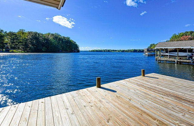 Lakefront home with spacious deck, dock, game room, hot tub, & sunset views