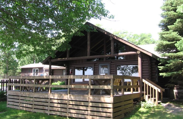Stunning Log Home on the water's edge with deck overlooking the swimming pool.