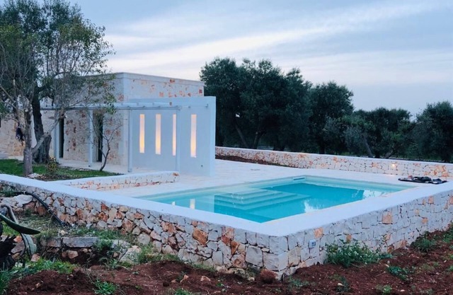 White stone typical apulian villa with barrel roof surrounded by olive trees.